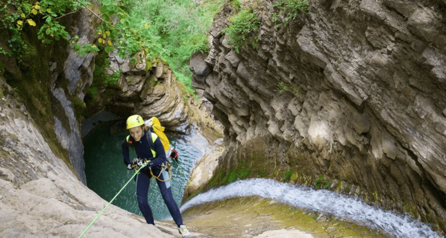 Adventurer canyoning down a waterfall in Canyon Nevidio.